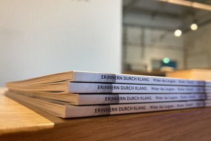 Exemplare einer Broschüre liegen in Nahaufnahme auf dem Infocounter am Denkort Bunker Valentin. Der Buchrücken zeigt den Titel "ERINNERN DURCH KLANG. Wider das Leugnen: Bunker 'Valentin'".