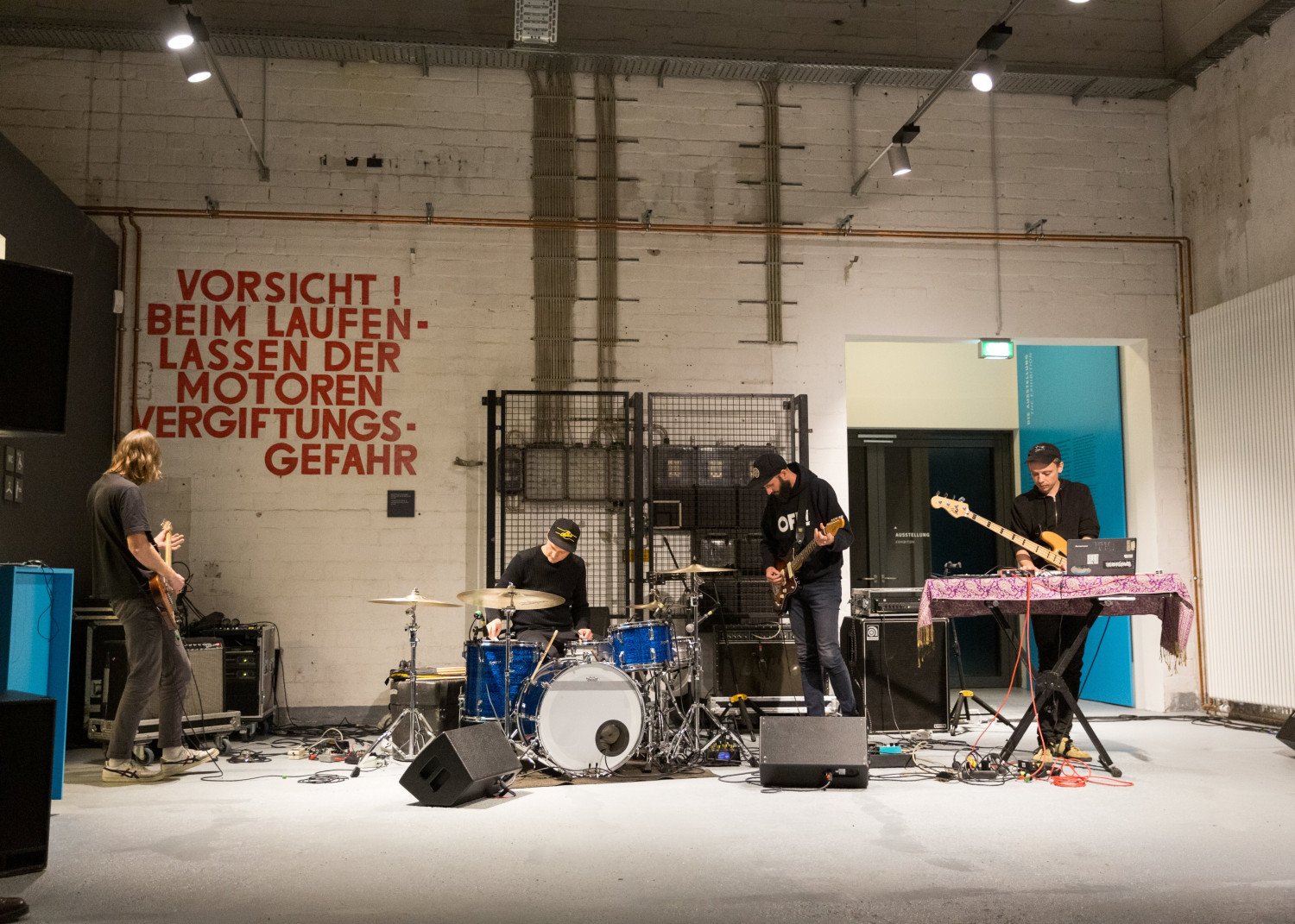 Vier Rock-Musiker mit ihren Instrumenten bei ihrem Auftritt im Infozentrum des Denkorts. 