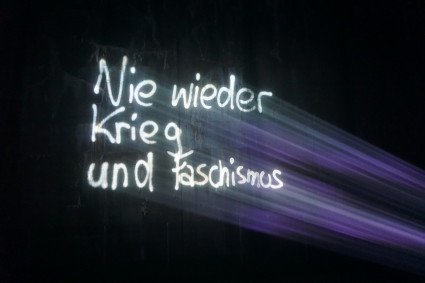 Große Projektion "Nie wieder Krieg und Faschismus" in weisser Schrift auf der Bunkerwand. 