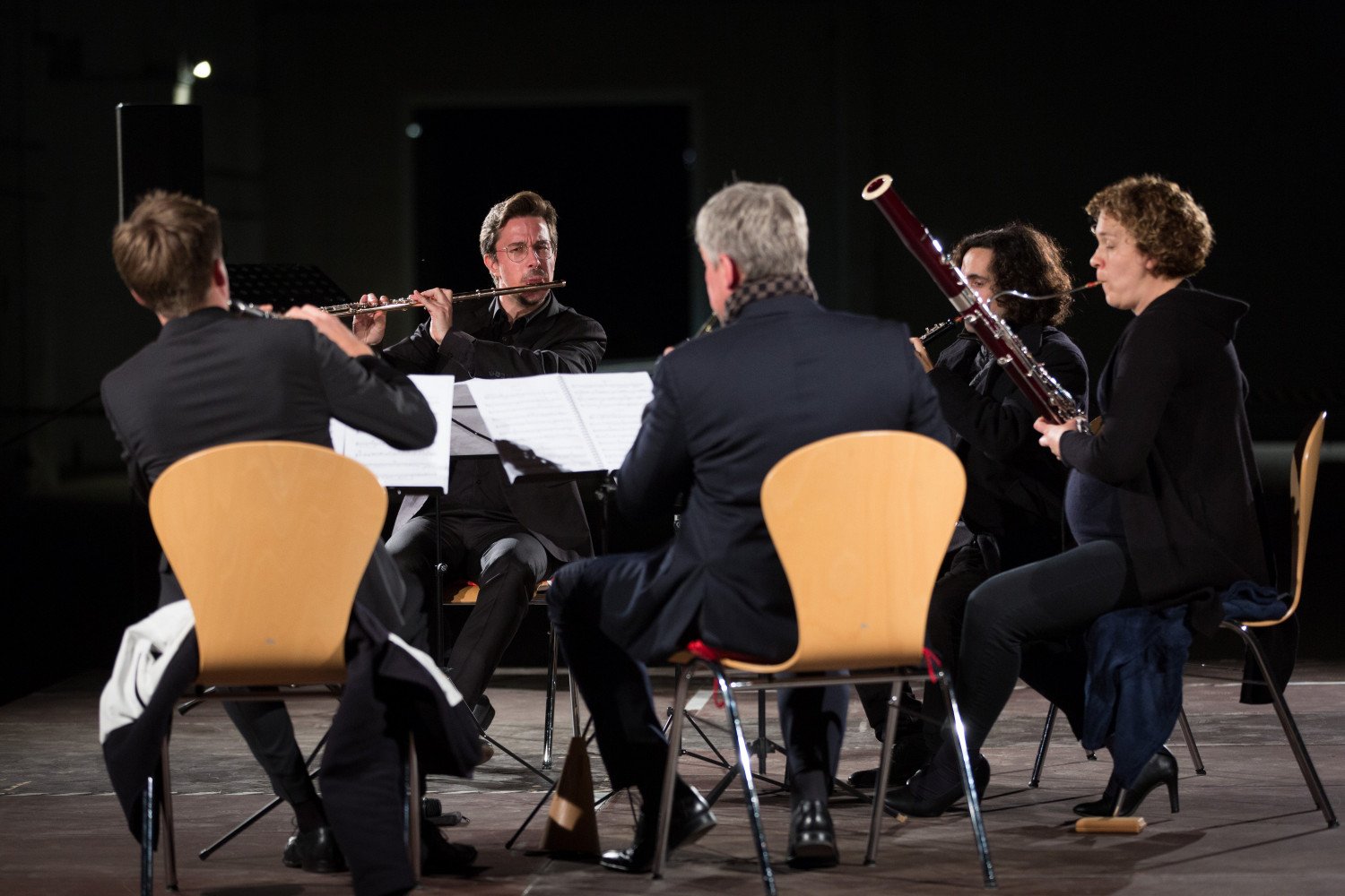 Fünf Musiker:innen beim Spieler ihrer Instrumente. Sie sitzen in einem kleinen Stuhlkreis zusammen.  