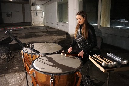 Eine junge Frau mit zwei großen Trommeln im Bunkerinnenraum.