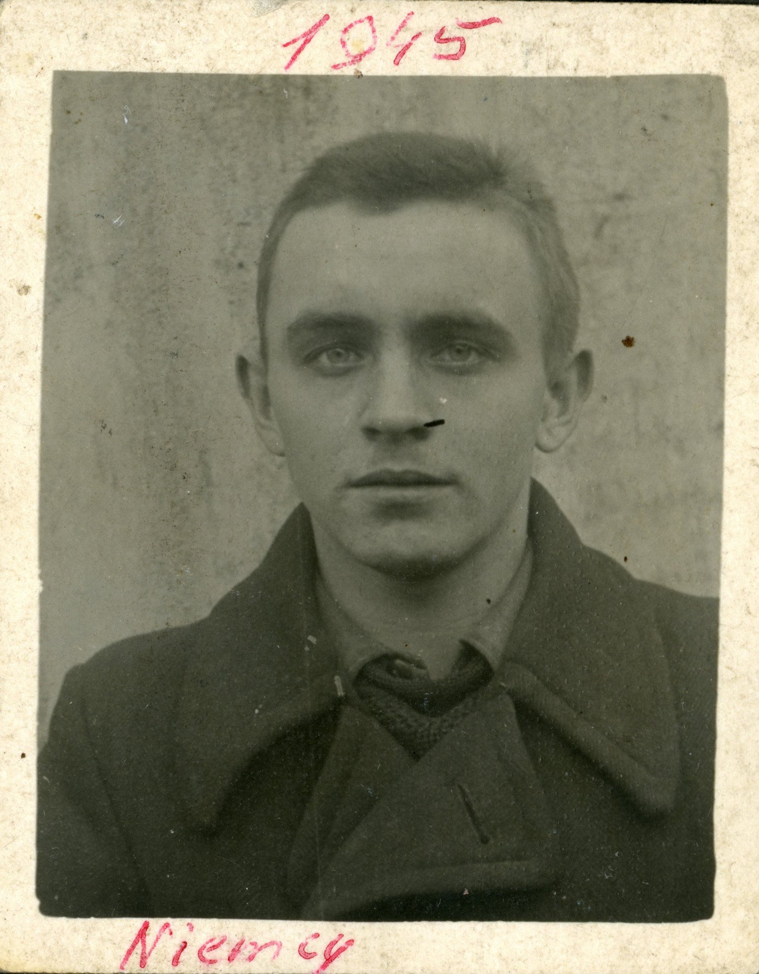 Abgebildet ist eine Nahaufnahme von einem Mann. Er trägt einen Mantel und hat kurze Haare. Er blickt direkt in die Kamera. 