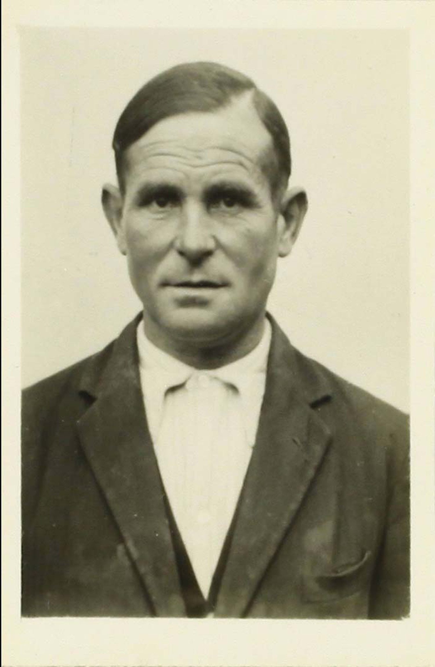 Ein altes Foto in schwarz-weiß Optik von Cayo Pelegay Villoque. Das Format ähnelt einem Passfoto. Er hat glatte, zur Seite gegeelte Haare und trägt einen Anzug mit Hemd darunter.  