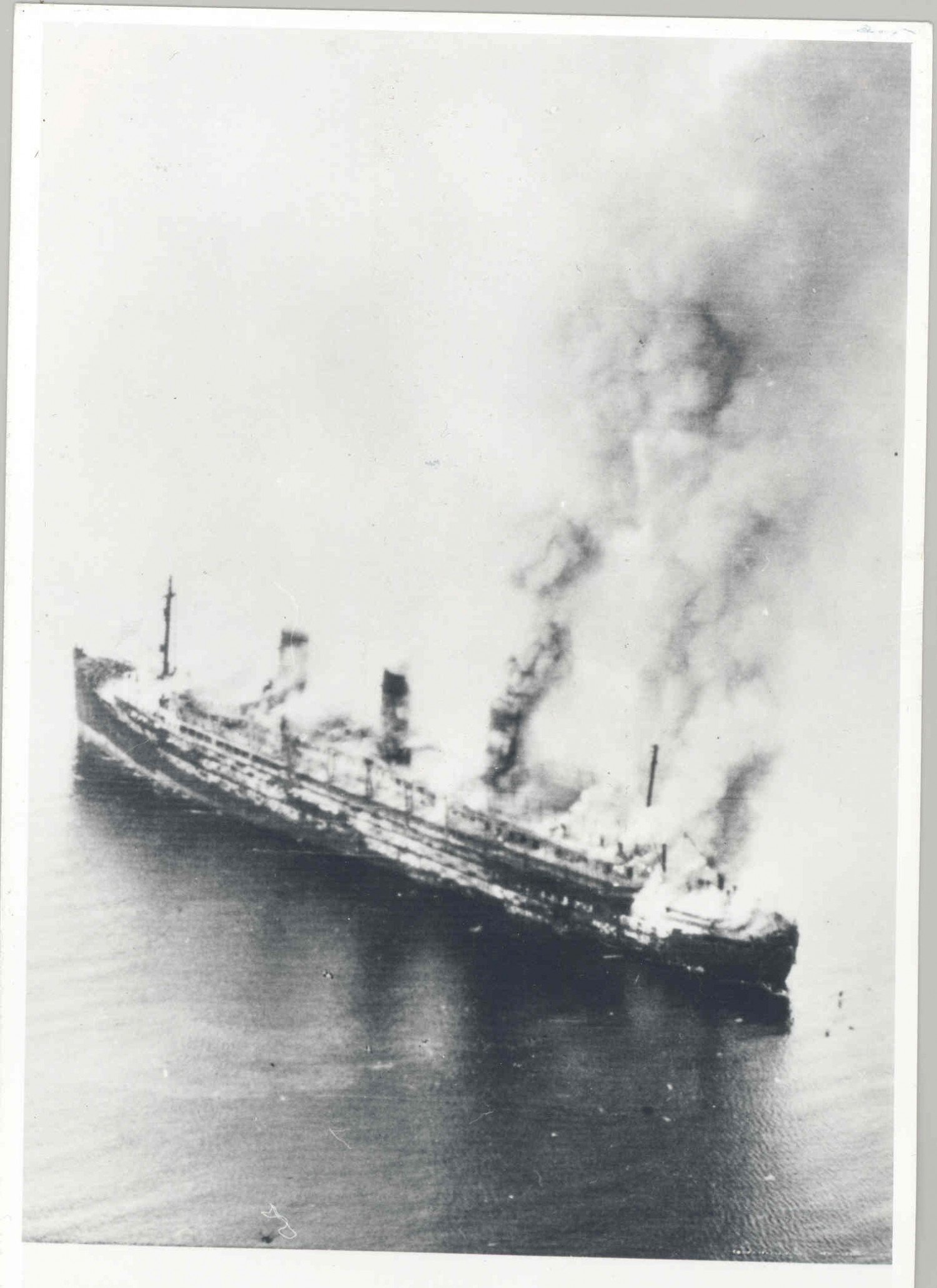 Gezeigt wird eine Luftaufnahme eines auf offener See brennendem Schiffes. 