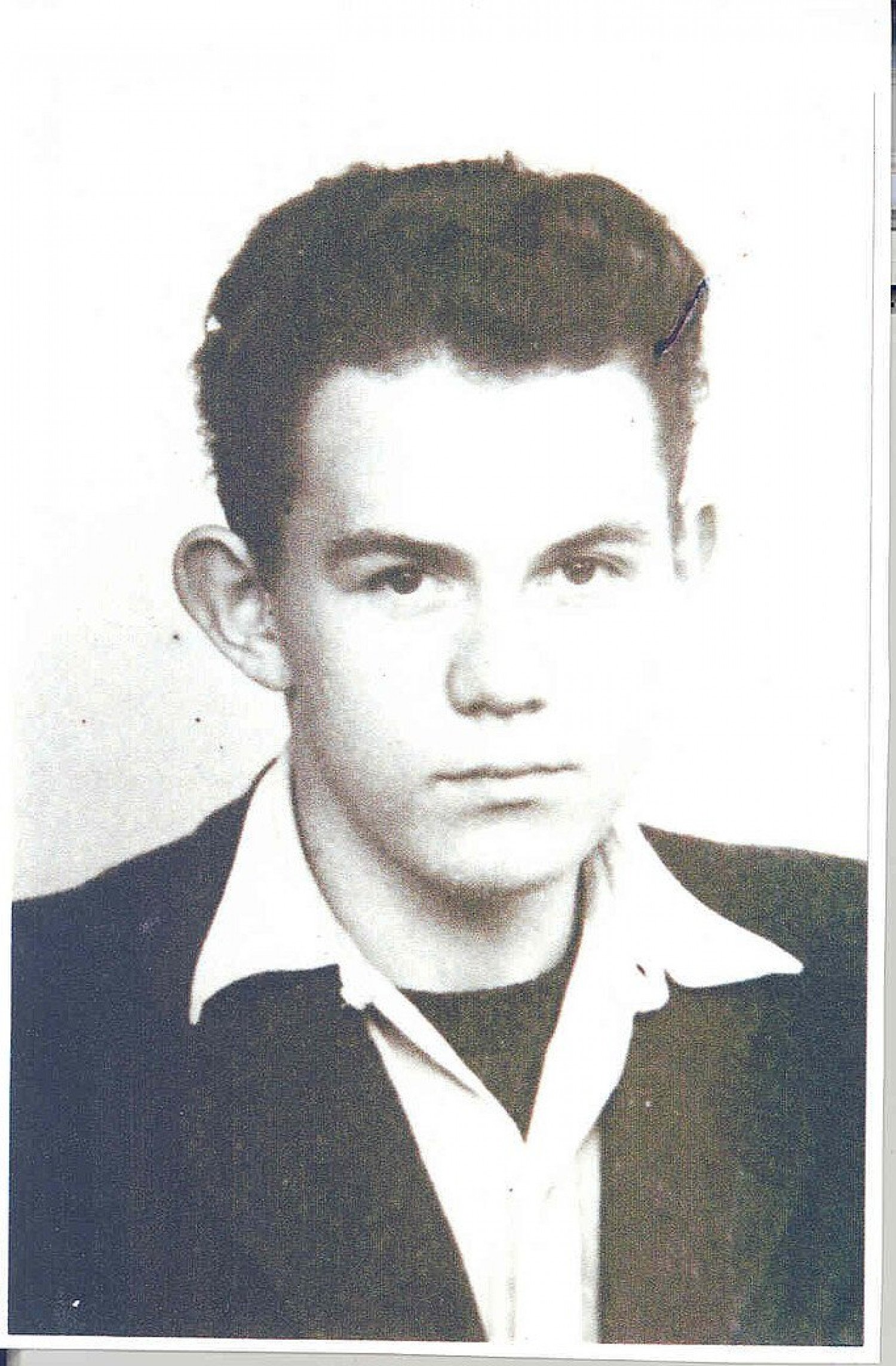 Abgebildet ist eine sepiafarbene Porträtaufnahme eines Mannes, der mit Anzug und Hemd gekleidet in die Kamera blickt.  