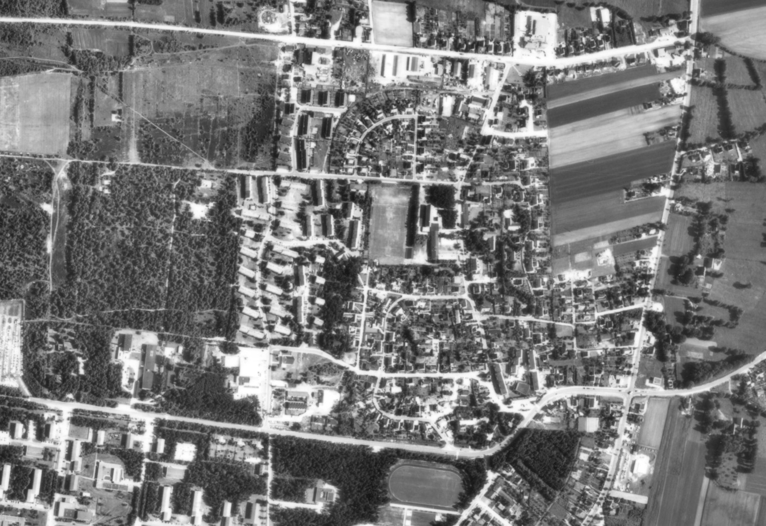 Abgebildet wird eine Luftaufnahme in schwarz-weiß vom Ort Heidkamp. 