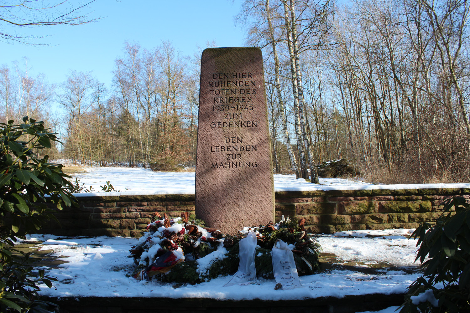 Abgebildet ist ein Mahnmal mit der Inschrift "Den hier ruhenden toten des Krieges 1939 bis 1945 zum Gedenken, den Lebenden zur Mahnung" 