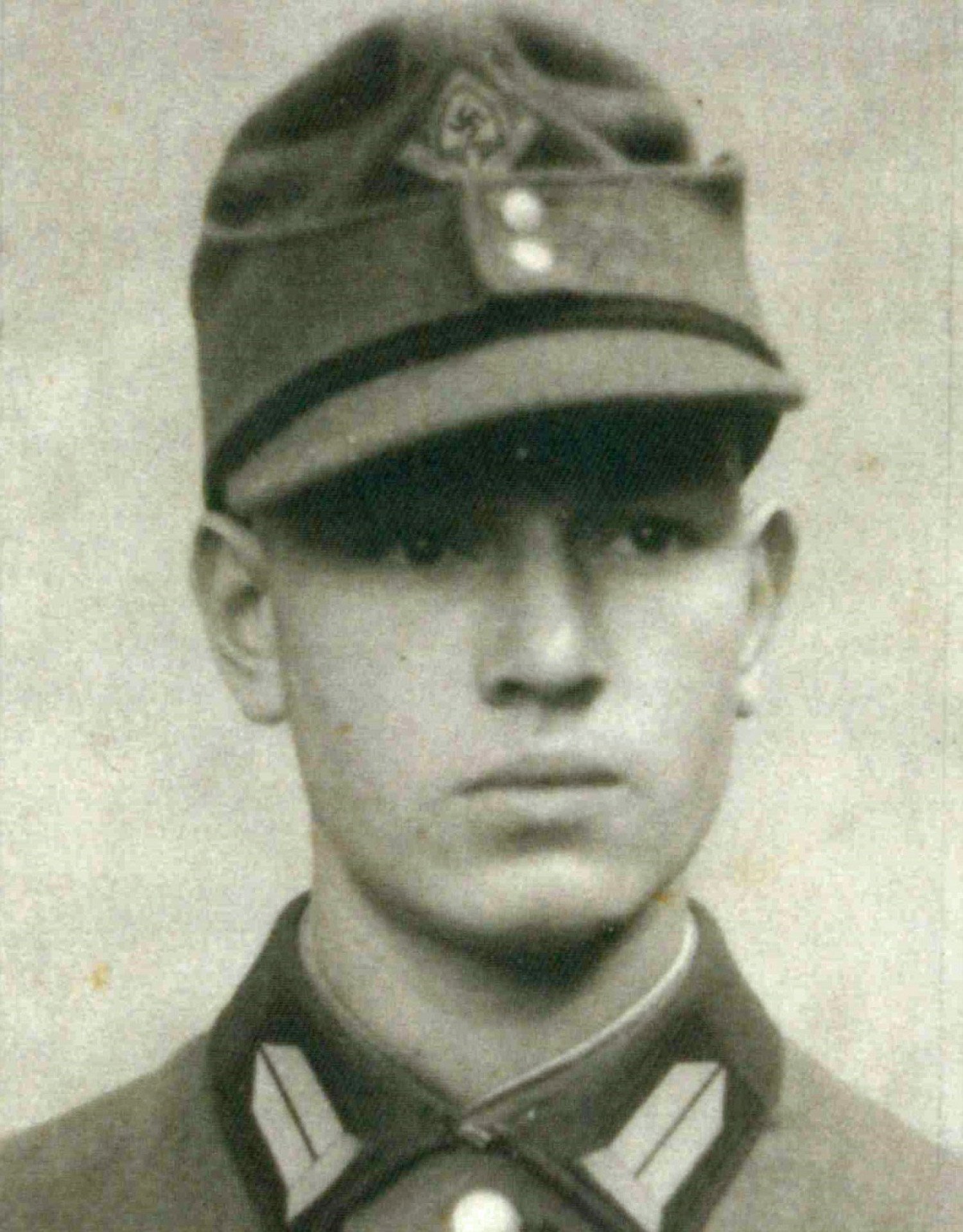 Abgebildet ist eine Porträtaufnahme von einem jungen Mann, welcher eine Kopfbedeckung anhat. Er blick nach rechts an der Kamera vorbei. 