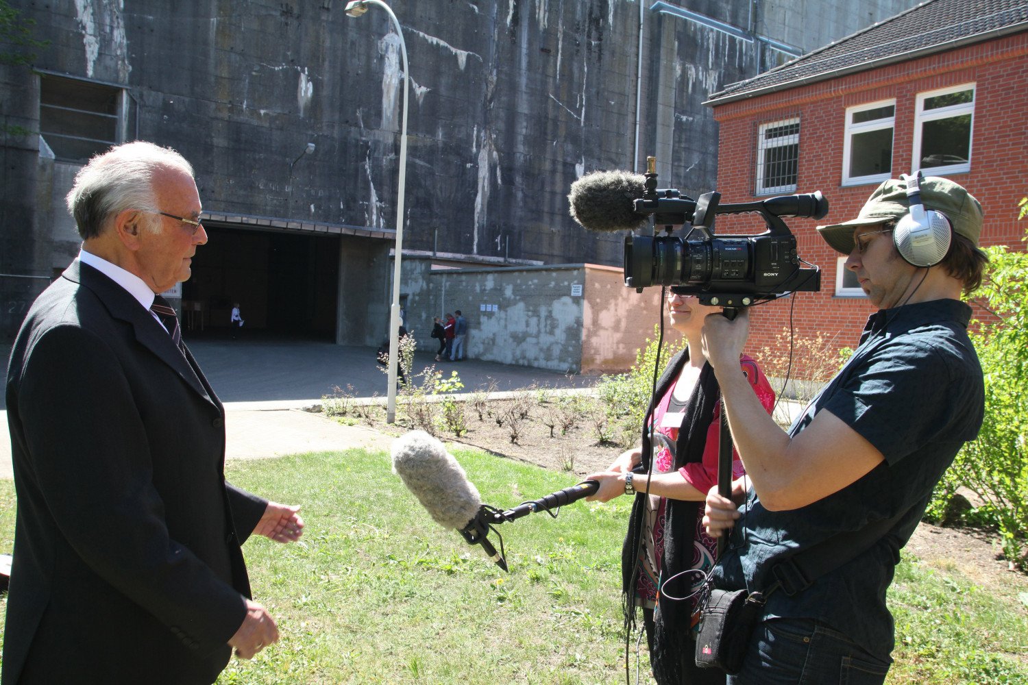 Erich Metz und ein Kamerateam vor der Fassade des Bunkers. 