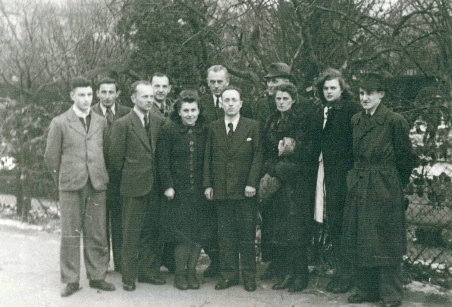 Gezeigt wird eine schwarz-weiß-Aufnahme, es handelt sich um ein Gruppenfoto. Es werden acht Männer und drei Frauen fotografiert. 