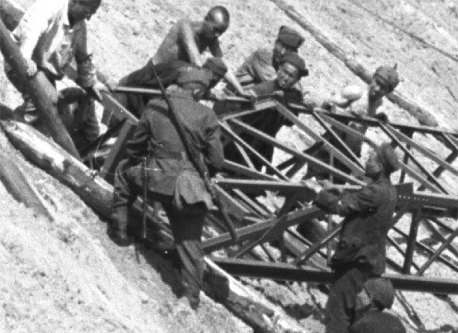 Ein Soldat packt am Gerüst mit an, so dass die Gruppe es gemeinsam bewegen kann.  